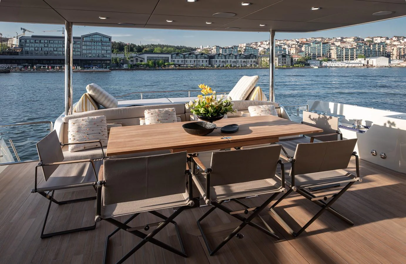 The aft deck features a stylish dining area with a wooden table and comfortable chairs, perfect for alfresco meals with a scenic view. aboard NUMARINE 27XP#6 Yacht for Sale