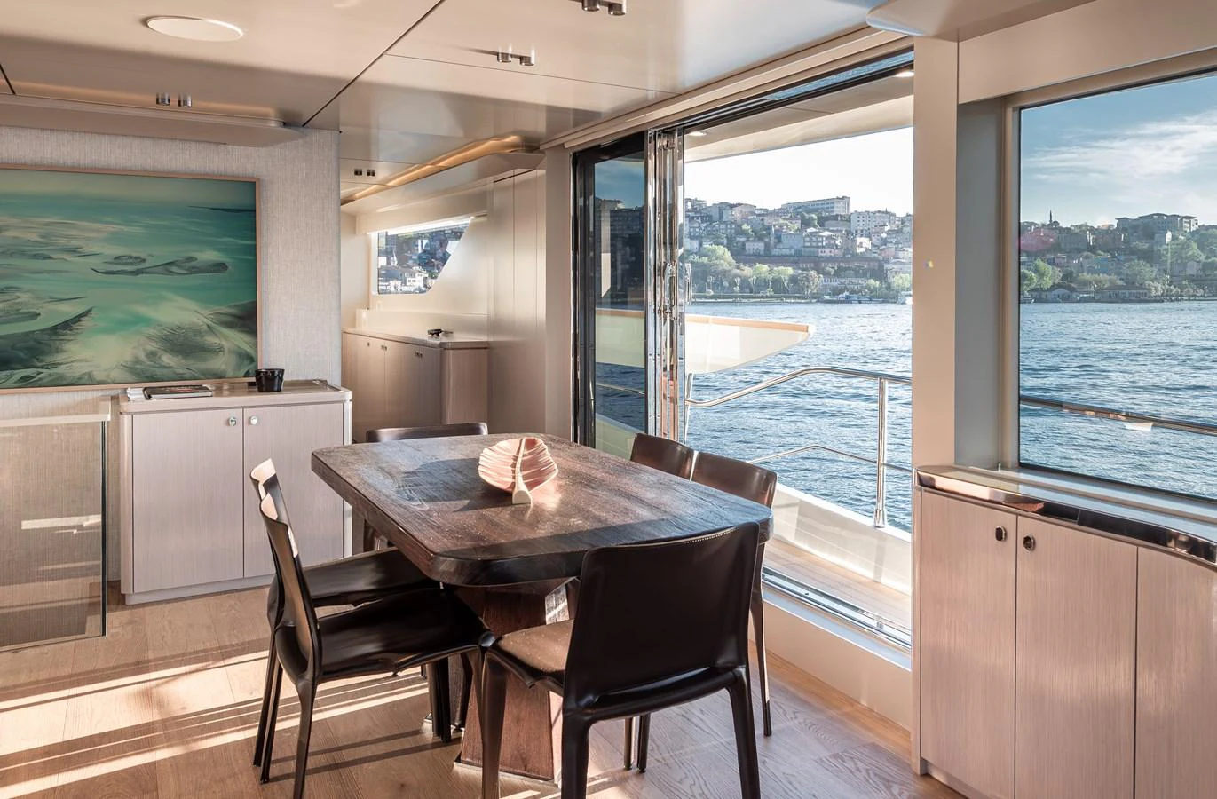 The yacht's dining area offers a serene view of the water through large windows, complemented by modern furnishings. aboard NUMARINE 27XP#6 Yacht for Sale