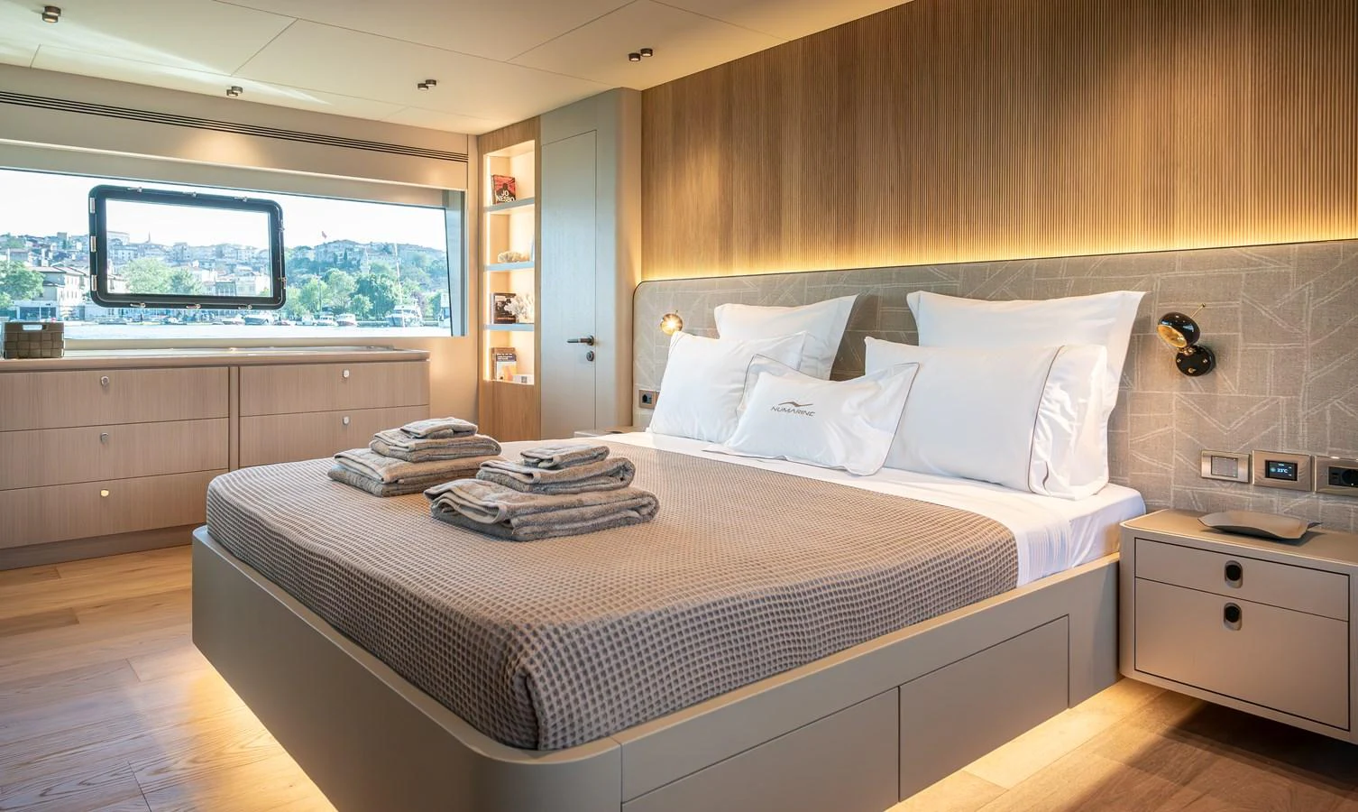 A luxurious stateroom featuring a large bed with neatly arranged linens and a scenic window view. aboard NUMARINE 27XP#6 Yacht for Sale