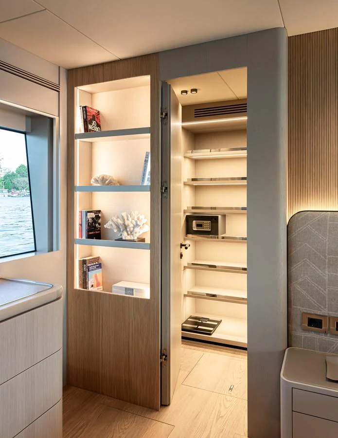 A well-organized storage area with shelves and a safe, illuminated by soft lighting. aboard NUMARINE 27XP#6 Yacht for Sale