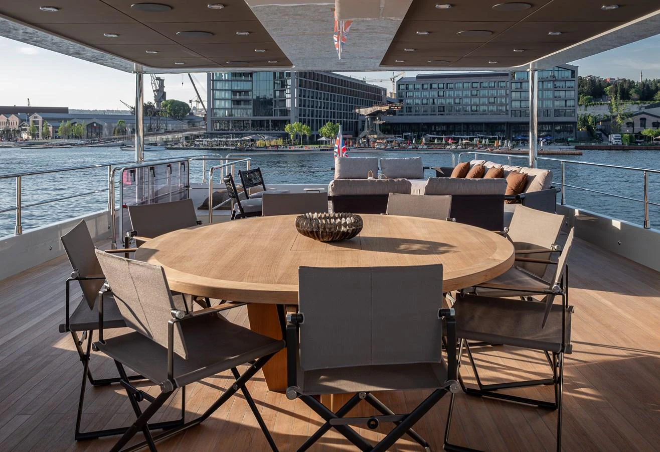 The aft deck features a spacious dining area with a large round table and comfortable chairs, perfect for alfresco dining. aboard NUMARINE 27XP#6 Yacht for Sale