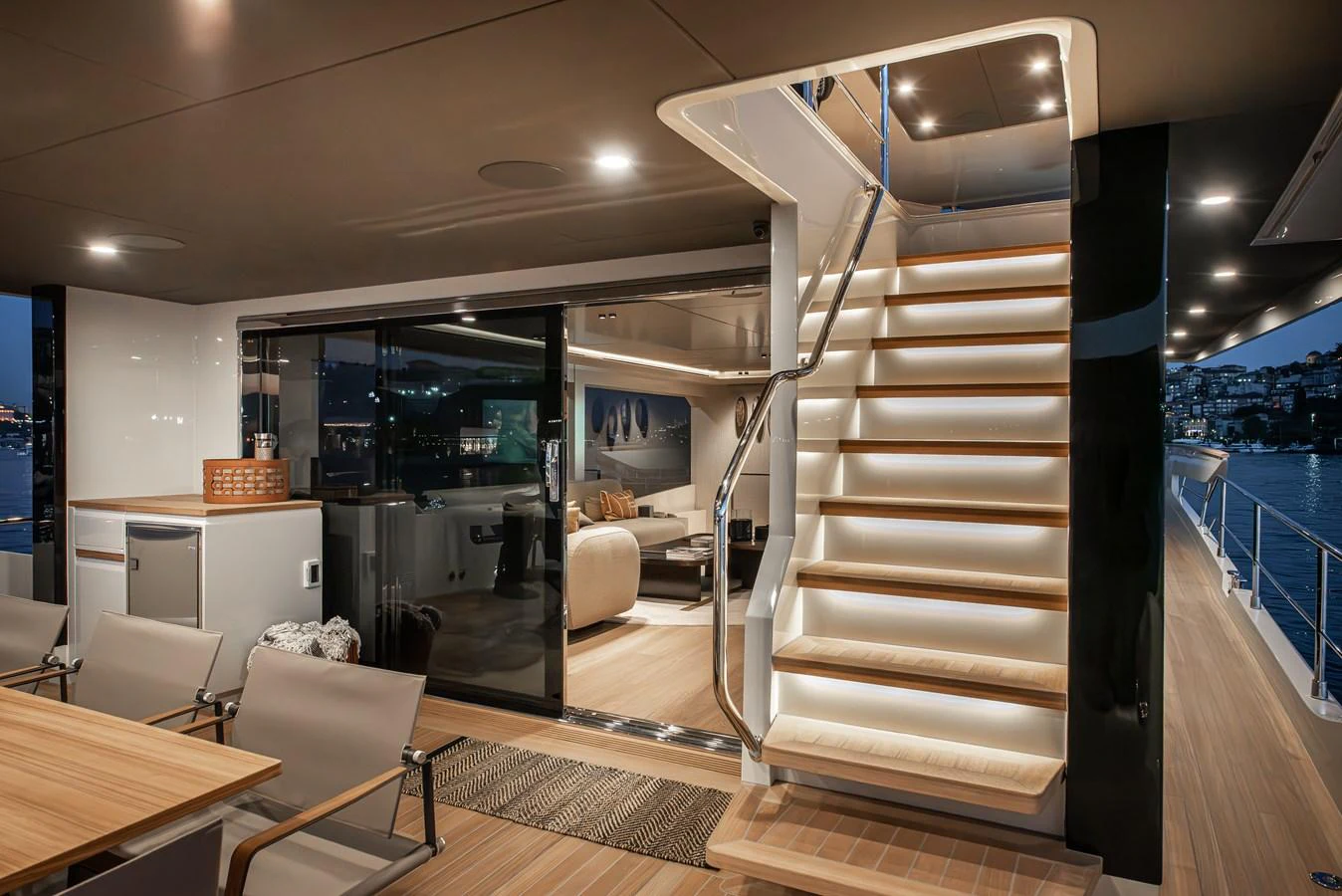 The aft deck features elegant seating and a staircase leading to the upper deck, with a view into the luxurious interior. aboard NUMARINE 27XP#6 Yacht for Sale