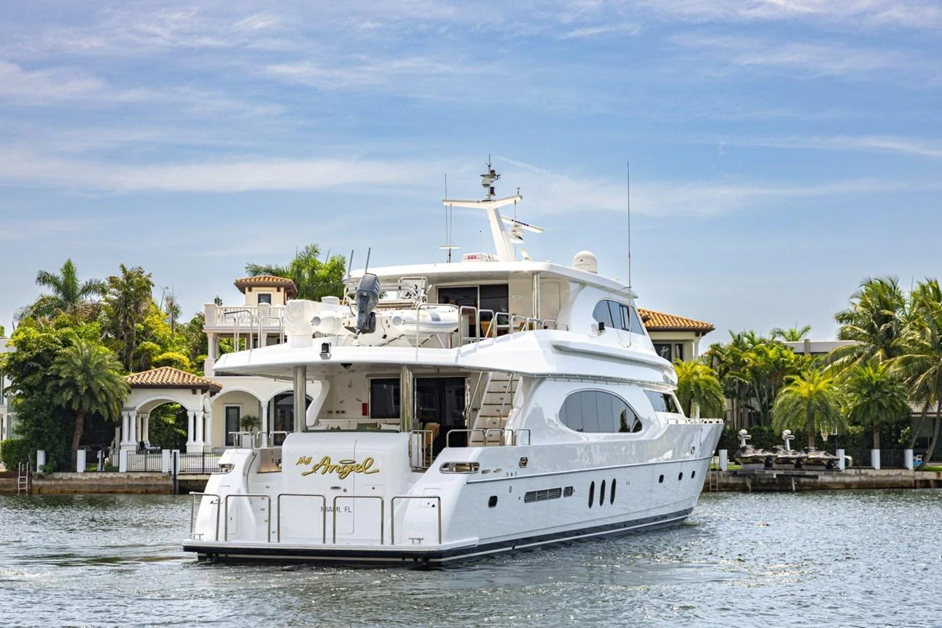 A luxurious yacht is anchored near a waterfront estate, showcasing its elegant design and spacious decks. aboard MY ANGEL Yacht for Sale