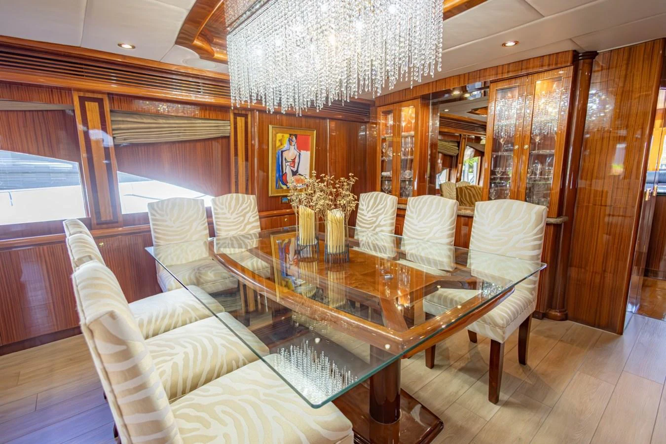 The yacht's dining area features a luxurious glass table with elegant seating and a stunning chandelier. aboard MY ANGEL Yacht for Sale
