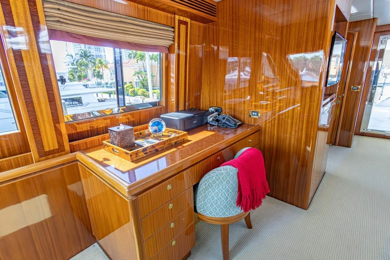 The yacht's interior features a polished wooden desk area with a view of the marina through large windows. aboard MY ANGEL Yacht for Sale