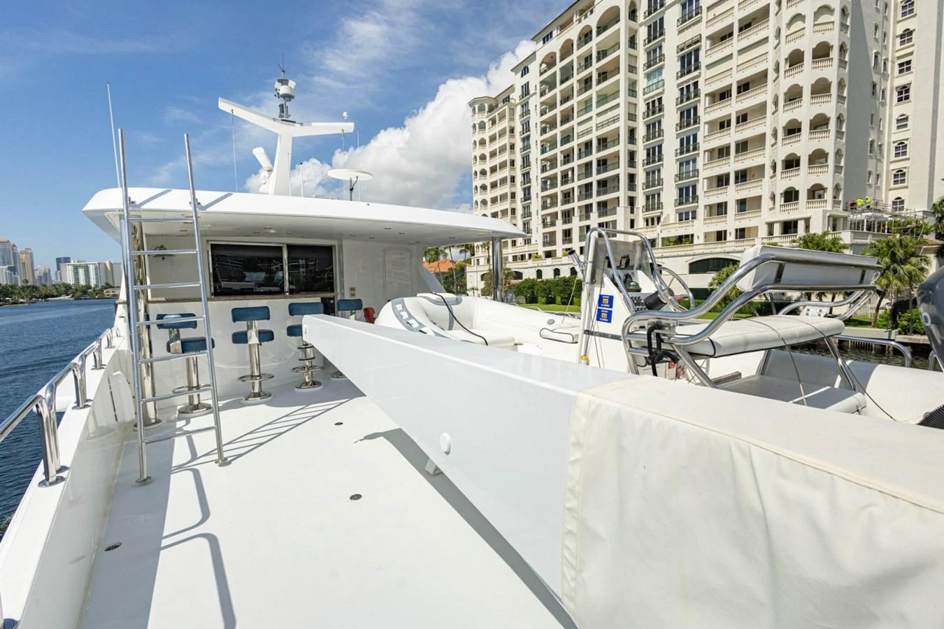The flybridge offers a spacious and open area with bar seating and a view of the surrounding buildings. aboard MY ANGEL Yacht for Sale