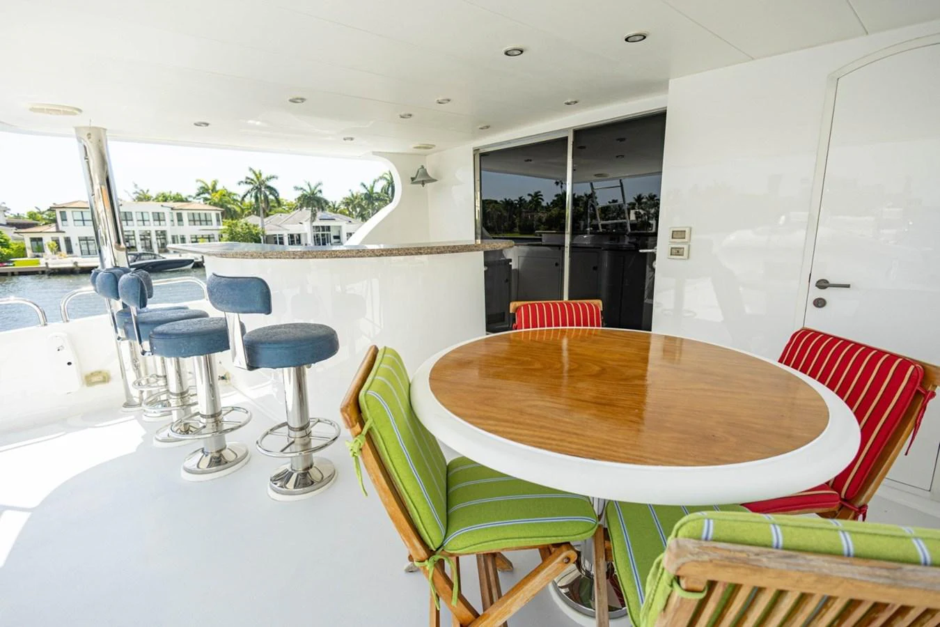 The aft deck features a stylish dining area with a round wooden table and colorful cushioned chairs, complemented by a bar with modern stools. aboard MY ANGEL Yacht for Sale