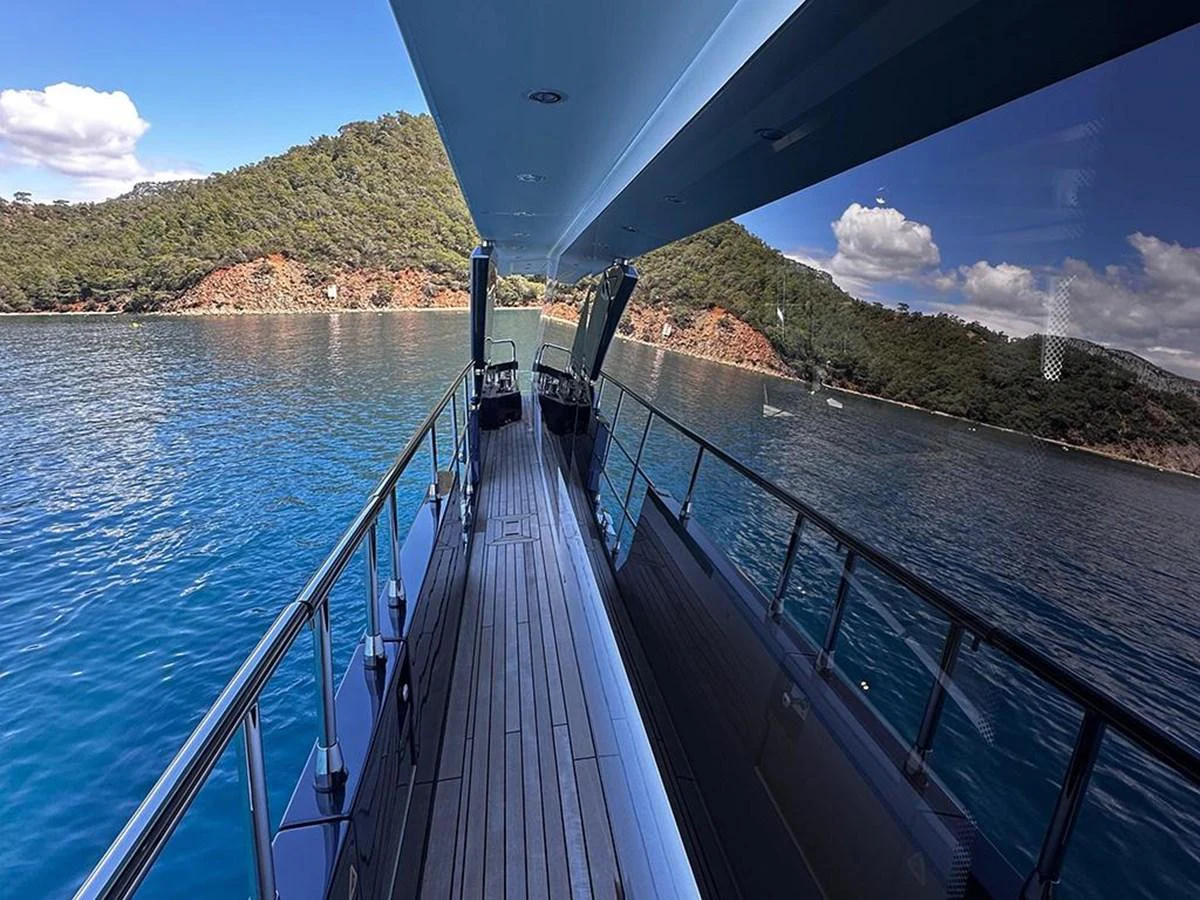 The side deck offers a serene view of the surrounding waters and lush landscape. aboard ALEX10 Yacht for Sale