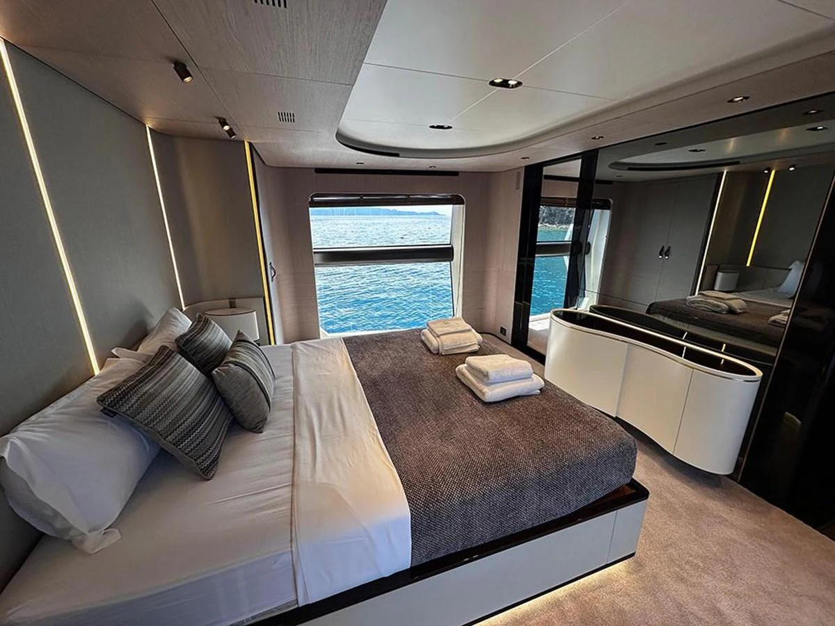 The master stateroom features a luxurious bed with a view of the sea through large windows. aboard ALEX10 Yacht for Sale