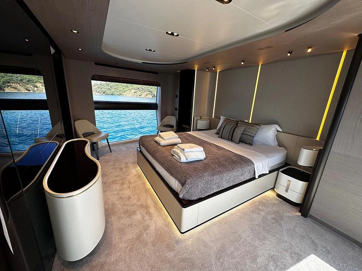 The master stateroom features a luxurious bed with elegant linens and ample natural light from large windows overlooking the sea. aboard ALEX10 Yacht for Sale