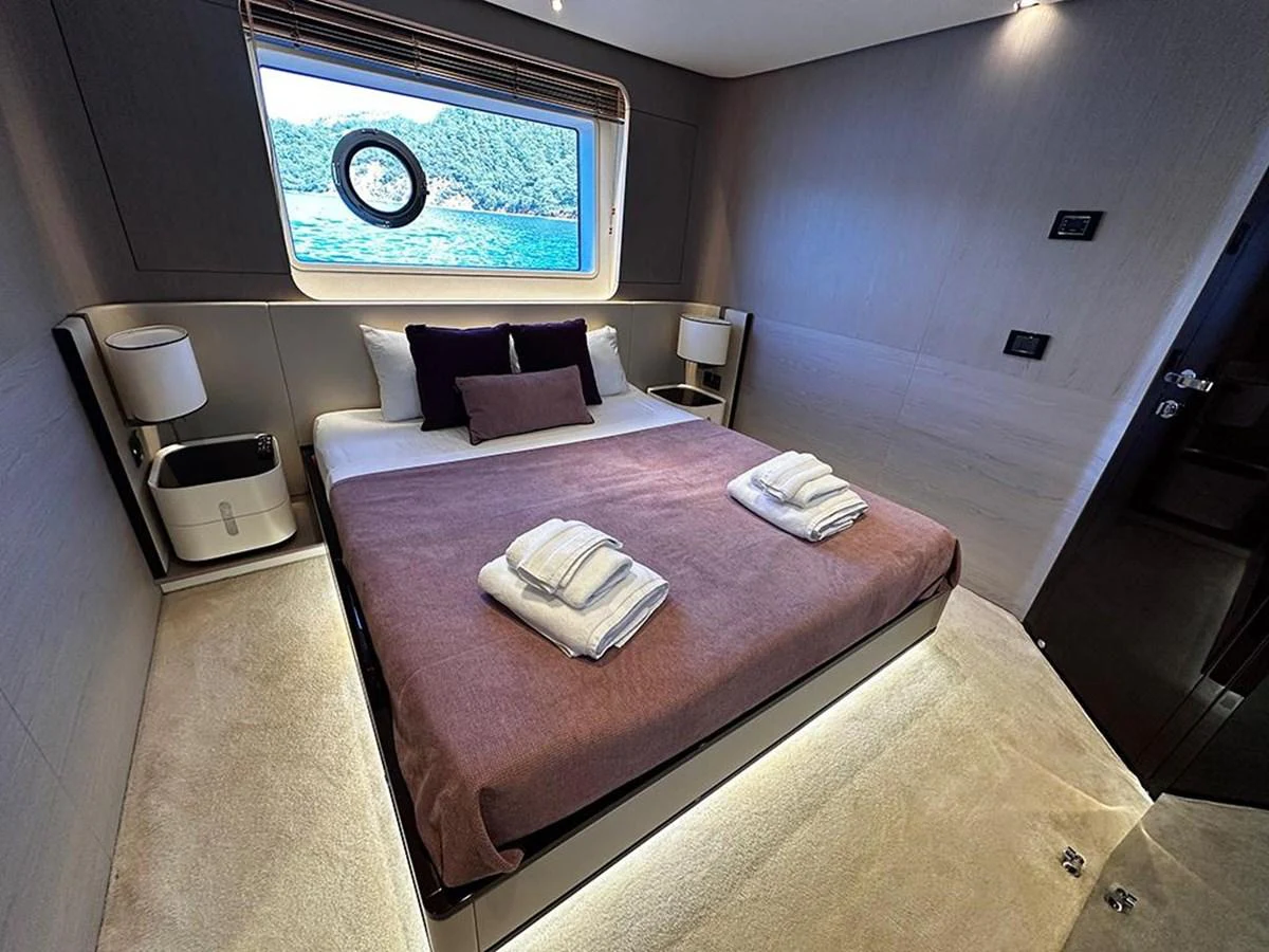 The stateroom features a plush bed with a view of the sea through a large window. aboard ALEX10 Yacht for Sale