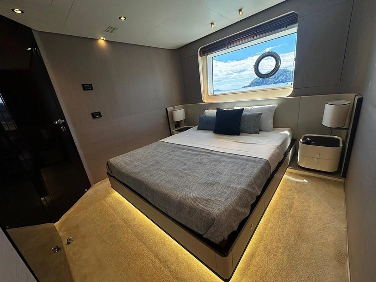 The stateroom features a luxurious bed with modern lighting and a scenic window view. aboard ALEX10 Yacht for Sale