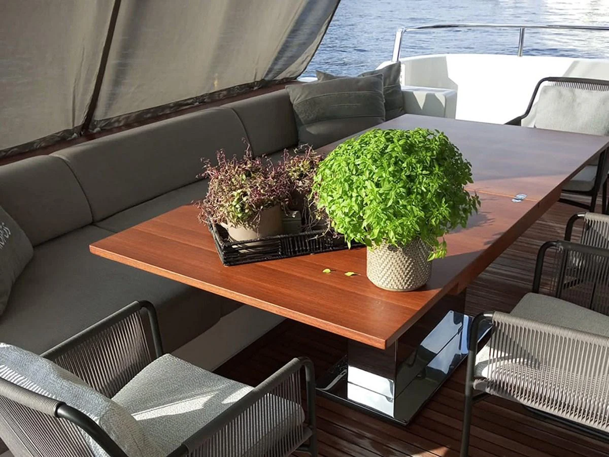 The aft deck features a stylish dining area with comfortable seating and lush greenery. aboard LA ISLA Yacht for Sale