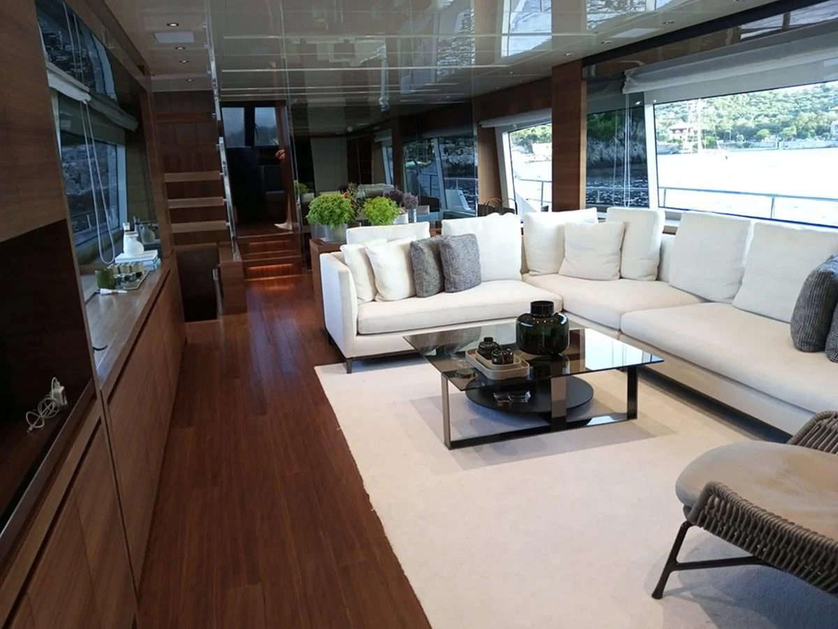 The salon features a spacious and elegant seating area with large windows offering stunning views. aboard LA ISLA Yacht for Sale