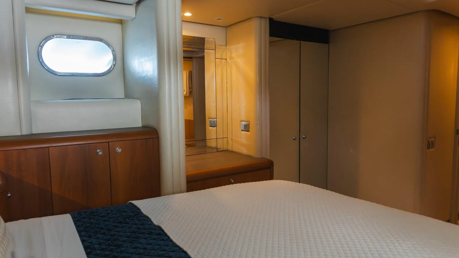 The stateroom features a cozy bed with elegant wood cabinetry and a small porthole window. aboard AUSSIE RULES Yacht for Sale