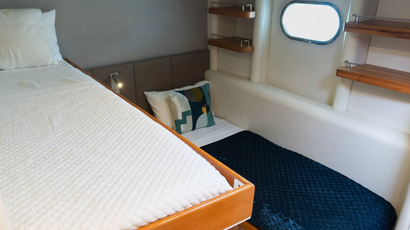 A cozy cabin featuring a bunk bed setup with modern decor and a small porthole window. aboard AUSSIE RULES Yacht for Sale