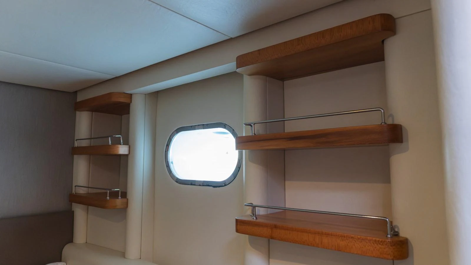 The yacht's interior features elegant wooden shelving and a small porthole window. aboard AUSSIE RULES Yacht for Sale