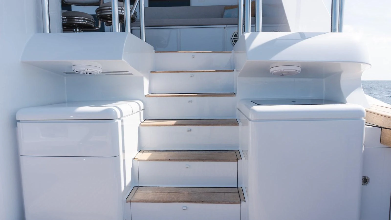 The yacht's aft deck features a set of steps leading up to a higher level, flanked by sleek white storage units. aboard AUSSIE RULES Yacht for Sale