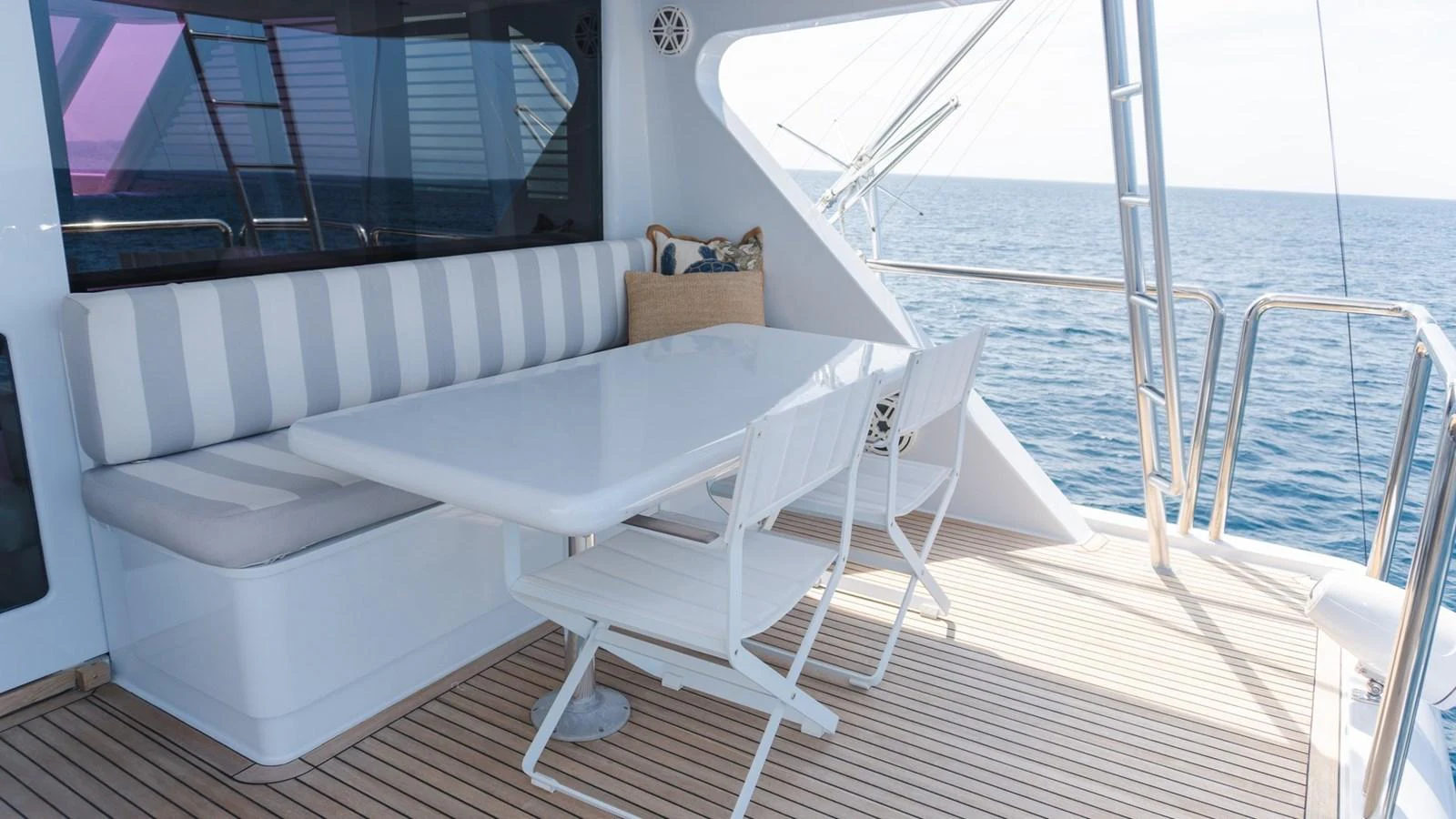 The aft deck features a stylish dining area with a white table and chairs, perfect for enjoying meals with an ocean view. aboard AUSSIE RULES Yacht for Sale