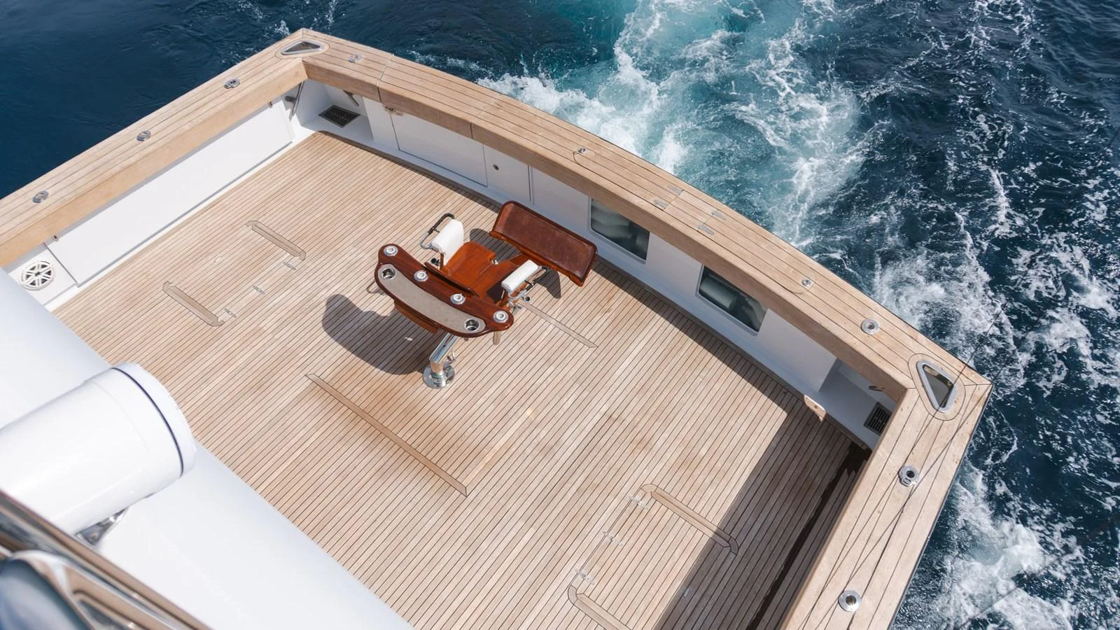 The yacht's aft deck features a spacious teak platform with a central fighting chair, perfect for sport fishing. aboard AUSSIE RULES Yacht for Sale