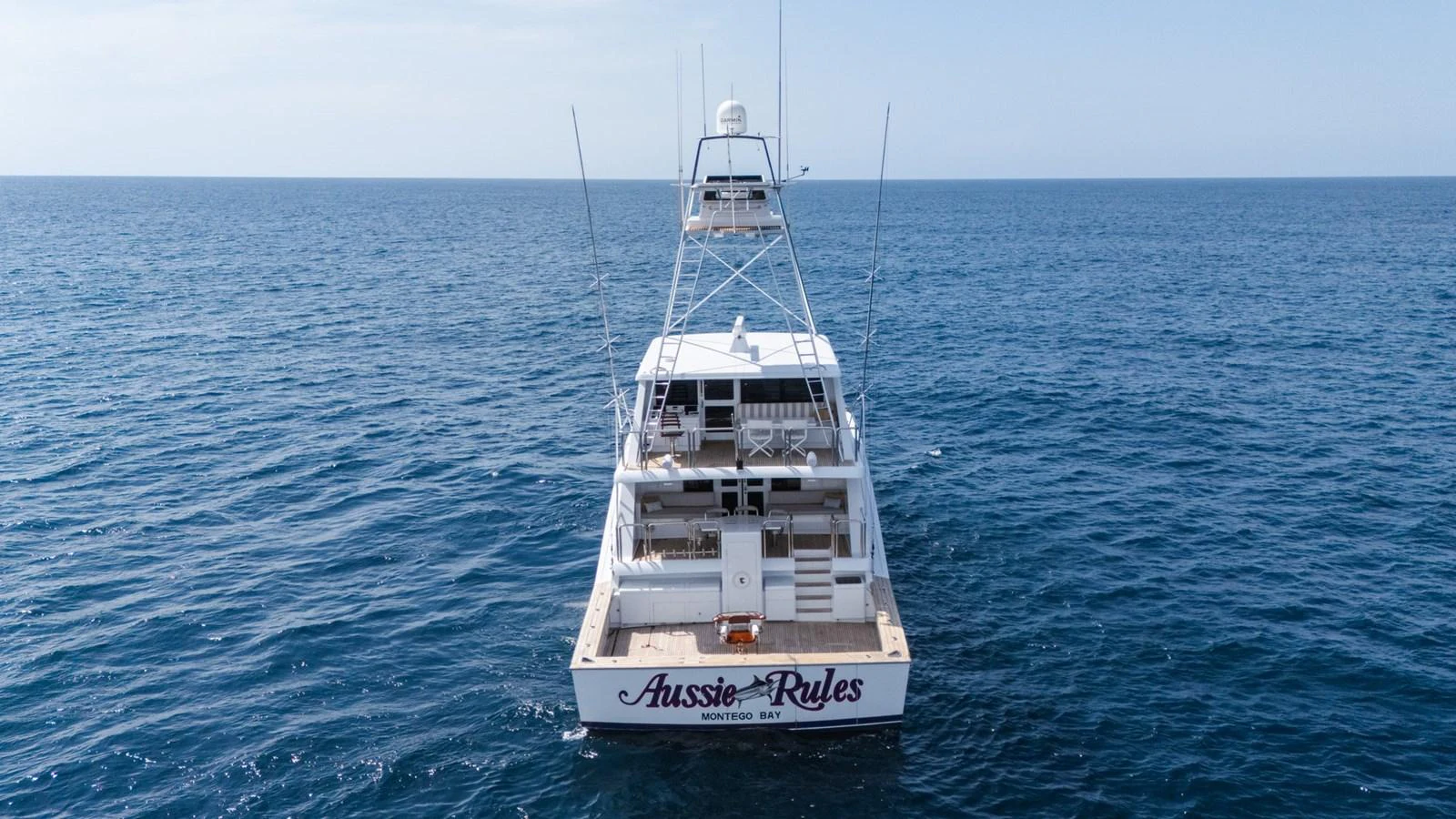 A sleek yacht cruising on open waters with a clear view of its stern. aboard AUSSIE RULES Yacht for Sale