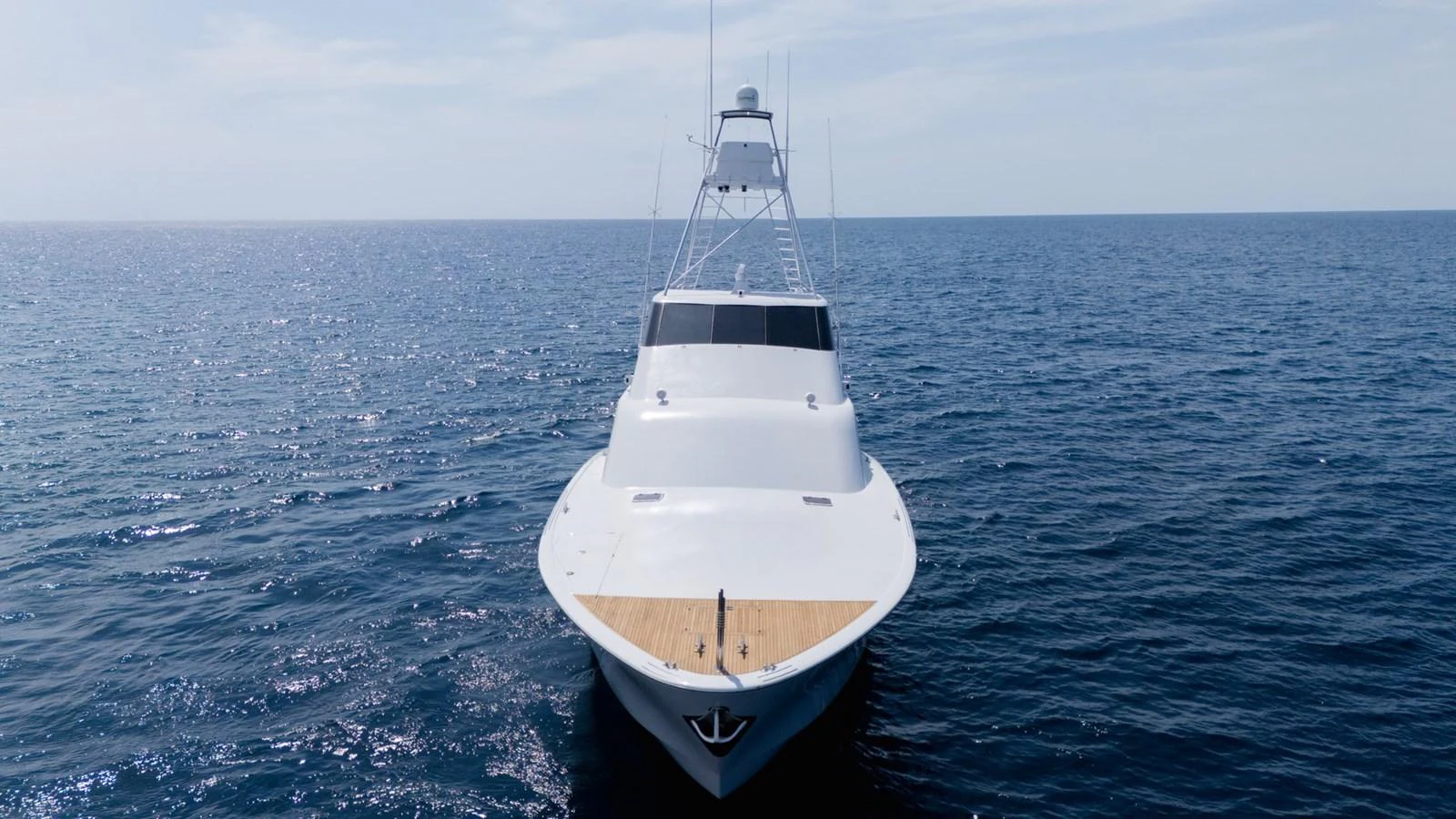 A sleek yacht cruises on calm blue waters under a clear sky. aboard AUSSIE RULES Yacht for Sale