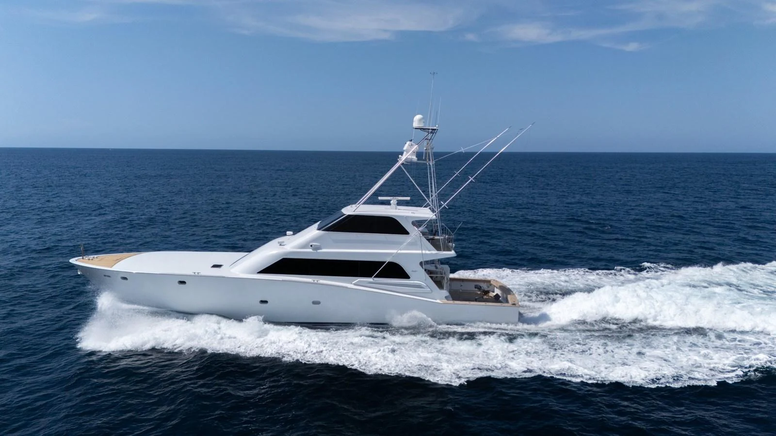 A sleek yacht cruises swiftly across the open sea under a clear blue sky. aboard AUSSIE RULES Yacht for Sale