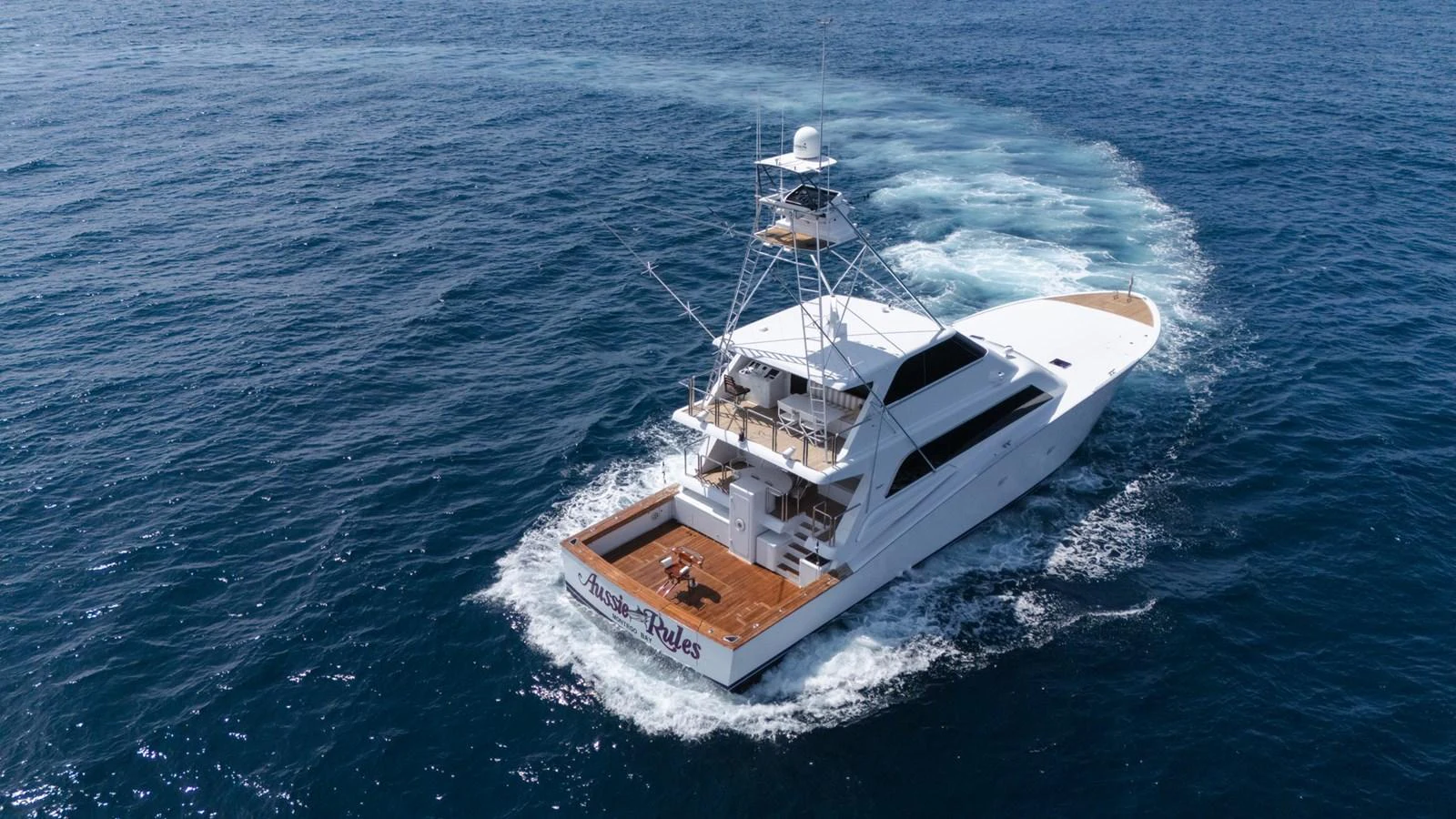 A sleek yacht cruises through the open sea, leaving a gentle wake behind. aboard AUSSIE RULES Yacht for Sale