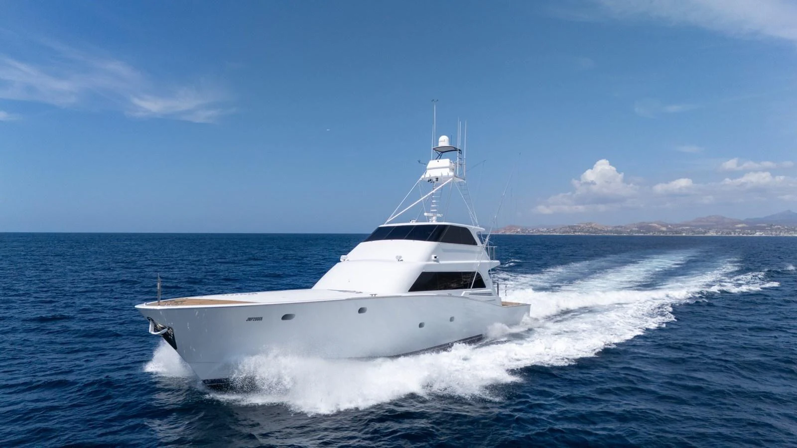 A sleek yacht cruises swiftly through the open sea under a clear blue sky. aboard AUSSIE RULES Yacht for Sale