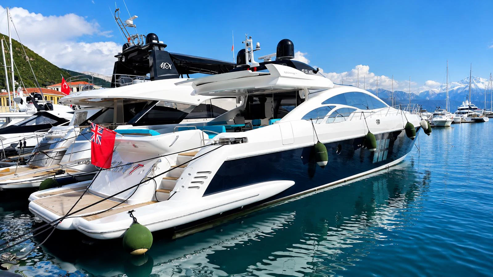 A sleek and modern yacht docked in a picturesque marina with clear blue waters and a mountainous backdrop. aboard AMAR T Yacht for Sale