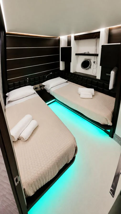 The twin stateroom features two single beds with modern lighting and elegant decor. aboard AMAR T Yacht for Sale