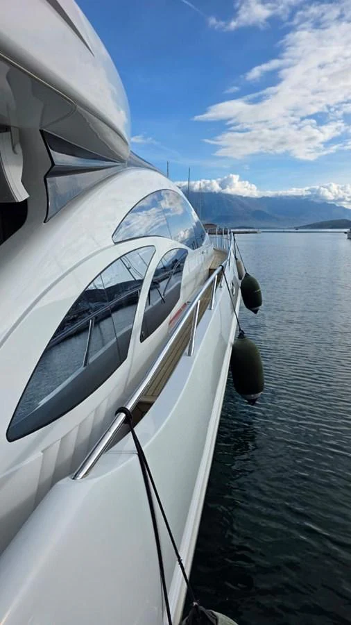 A sleek yacht is docked at a serene marina, reflecting the calm waters and clear sky. aboard AMAR T Yacht for Sale