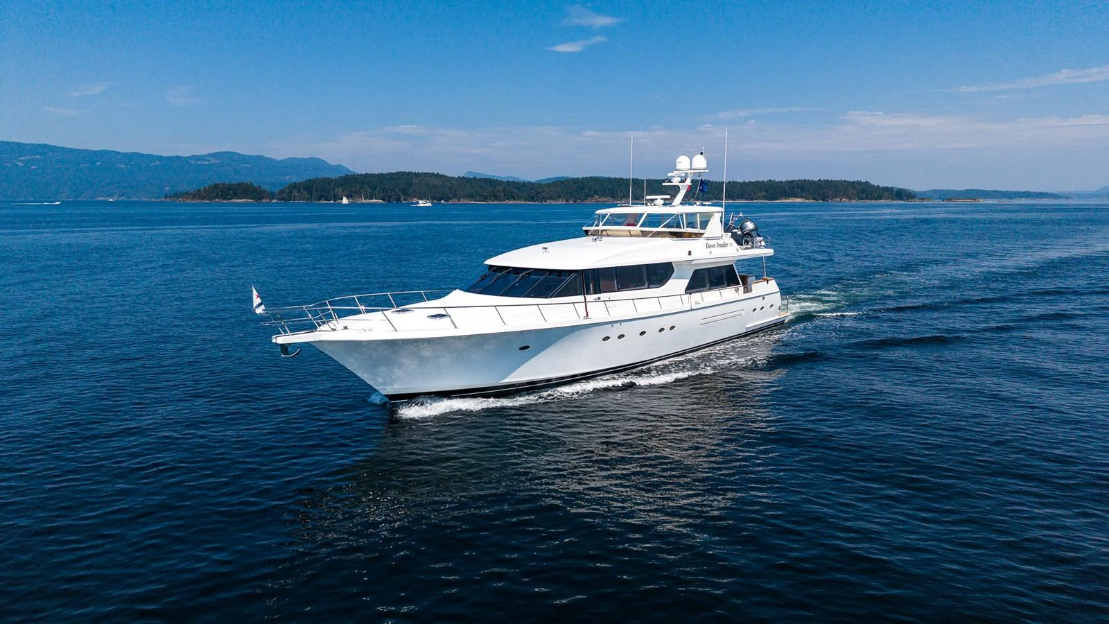 A sleek and elegant yacht cruises through calm blue waters under a clear sky. aboard DAWN TRADER VII Yacht for Sale