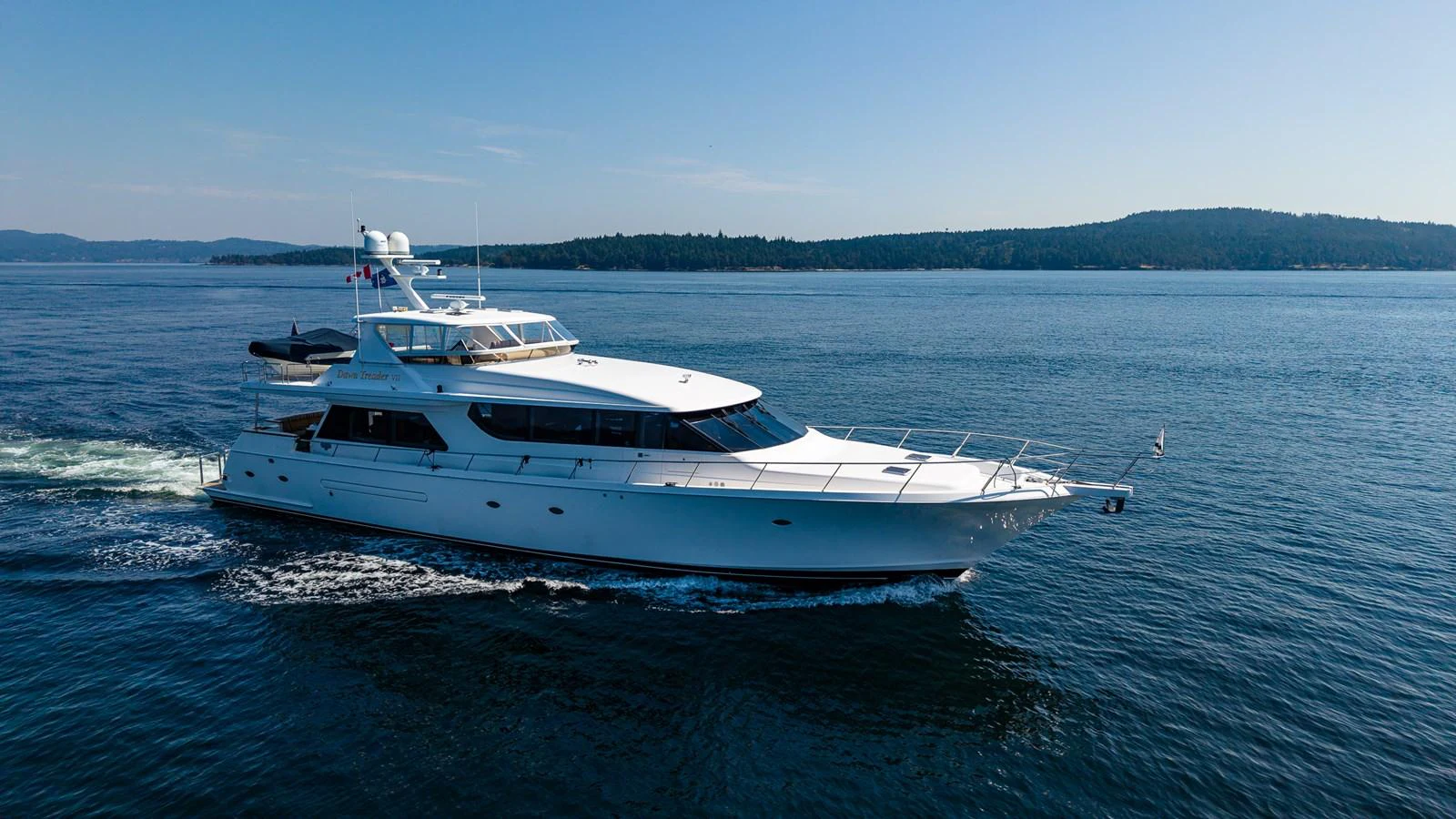 A sleek yacht glides through calm waters under a clear blue sky. aboard DAWN TRADER VII Yacht for Sale