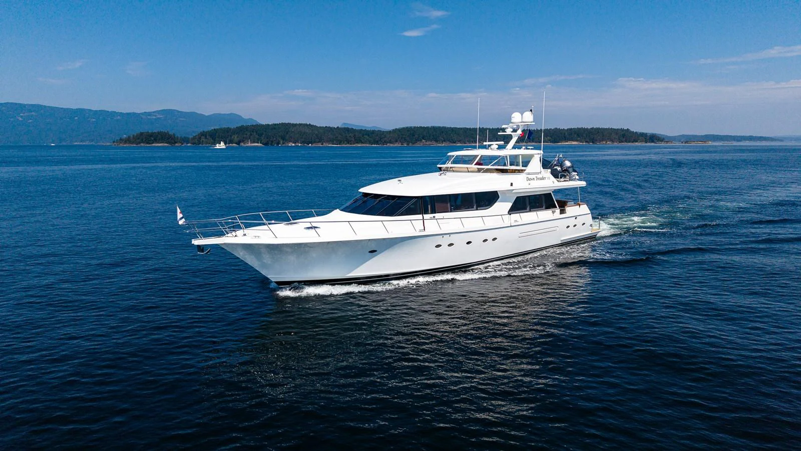 A sleek white yacht cruises gracefully on calm blue waters under a clear sky. aboard DAWN TRADER VII Yacht for Sale