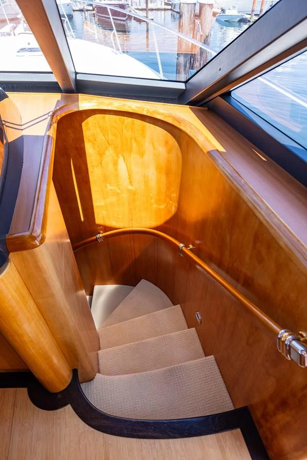 A beautifully crafted wooden staircase leads to the lower deck, illuminated by natural light from the windows above. aboard DAWN TRADER VII Yacht for Sale