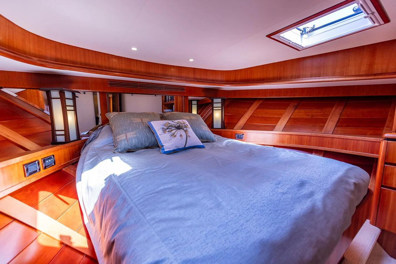 The stateroom features a cozy bed with elegant wood paneling and a skylight for natural light. aboard DAWN TRADER VII Yacht for Sale