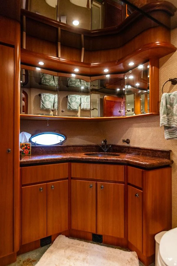 The yacht's bathroom features elegant wood cabinetry, a granite countertop, and mirrored storage. aboard DAWN TRADER VII Yacht for Sale