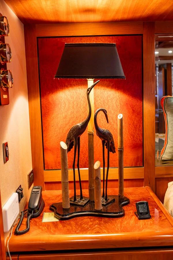 A stylish lamp with bird sculptures adorns a wooden table in a yacht's interior. aboard DAWN TRADER VII Yacht for Sale