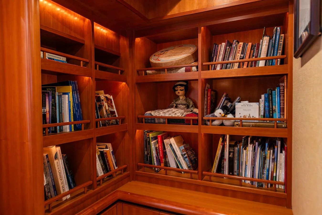 A cozy onboard library with warm wood tones and a variety of books. aboard DAWN TRADER VII Yacht for Sale