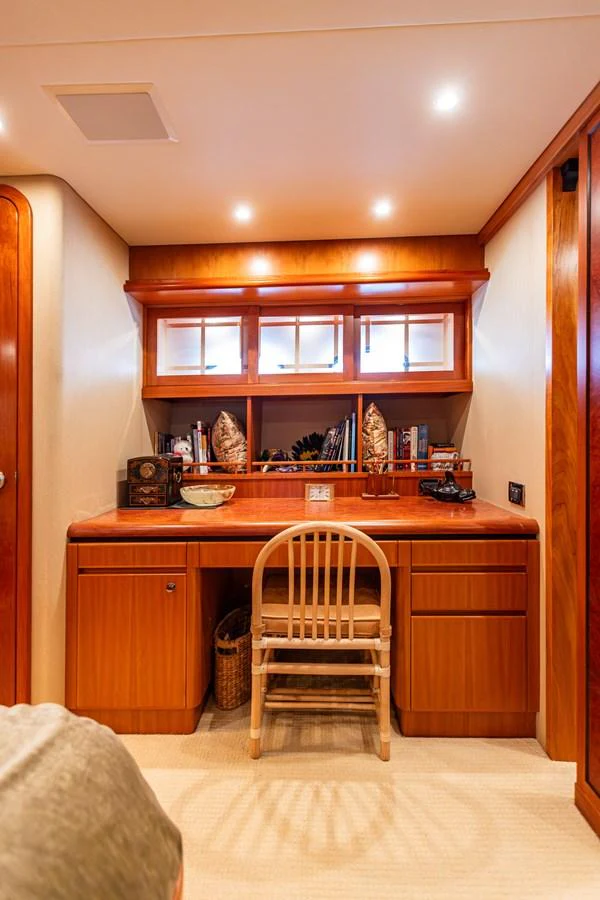 A cozy yacht office space with a wooden desk and built-in shelving, perfect for work or study. aboard DAWN TRADER VII Yacht for Sale