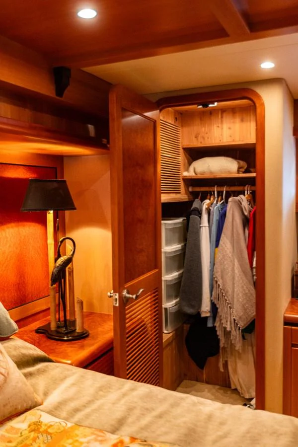 A cozy stateroom with a neatly organized closet and warm lighting. aboard DAWN TRADER VII Yacht for Sale