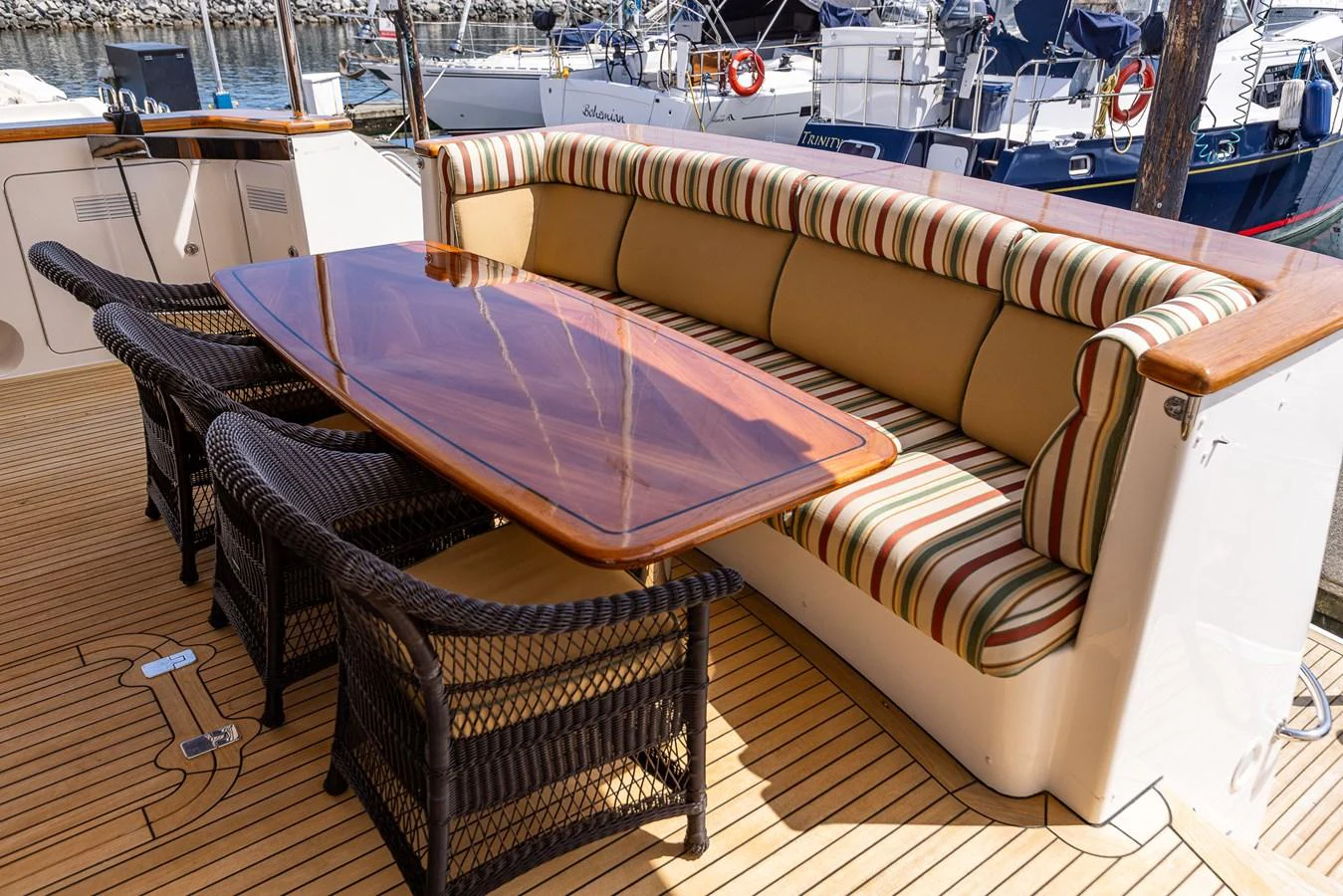 The aft deck features a stylish dining area with a polished wooden table and comfortable seating. aboard DAWN TRADER VII Yacht for Sale