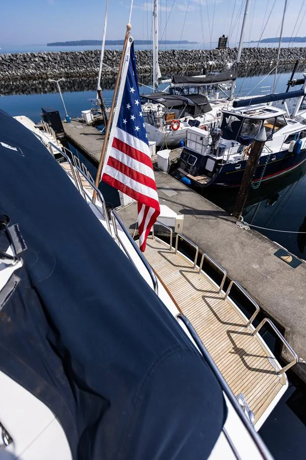 The aft deck of the yacht features a flag and offers a view of the marina. aboard DAWN TRADER VII Yacht for Sale