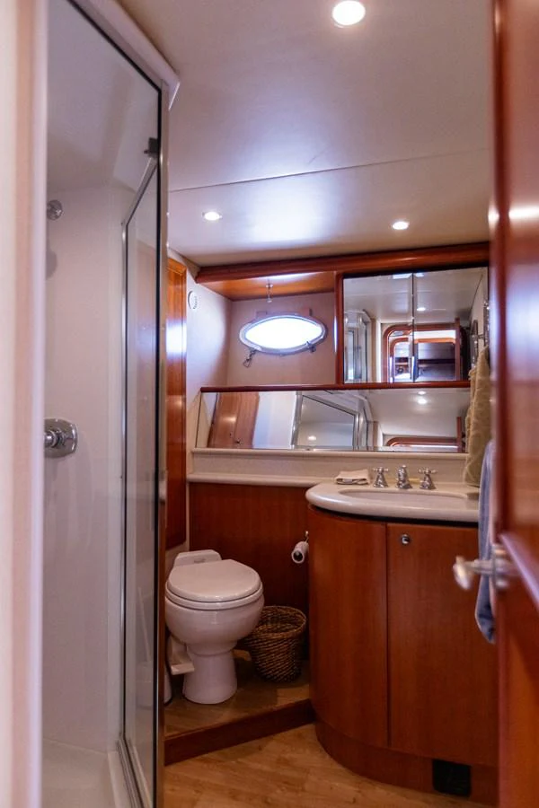 The yacht's bathroom features a modern shower, elegant wood cabinetry, and a well-lit vanity area. aboard DAWN TRADER VII Yacht for Sale