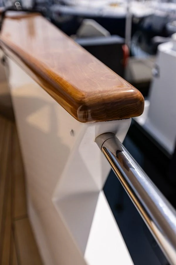 A close-up view of a polished wooden handrail and stainless steel support on the yacht. aboard DAWN TRADER VII Yacht for Sale