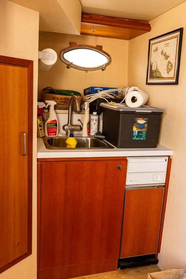 A compact yacht galley with a sink, storage, and cleaning supplies. aboard DAWN TRADER VII Yacht for Sale