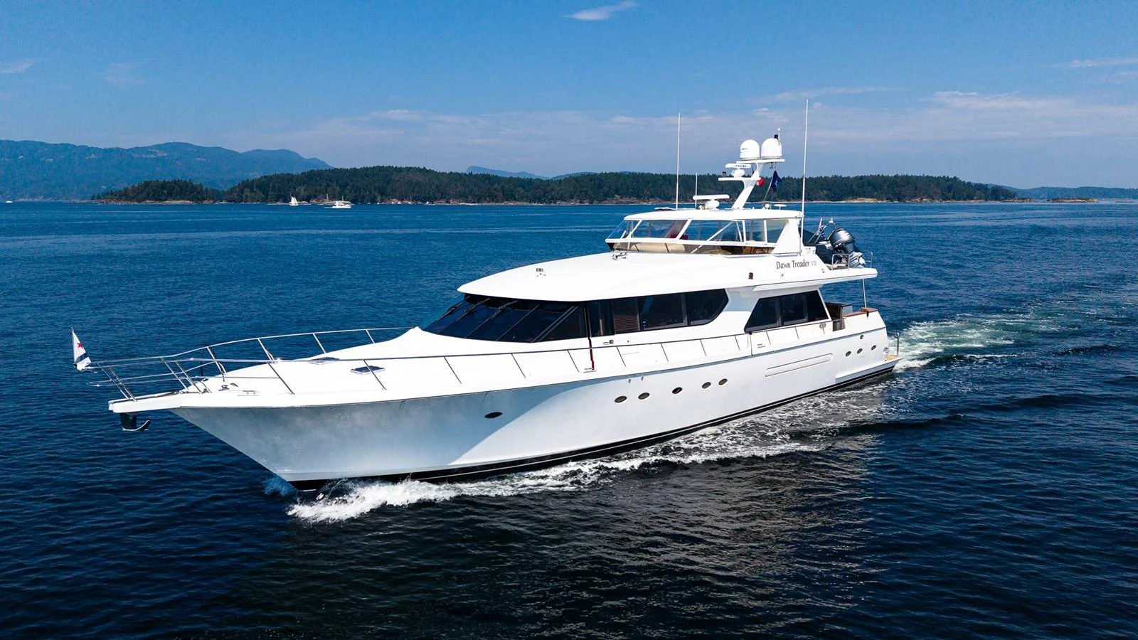 A sleek white yacht cruises through calm blue waters under a clear sky. aboard DAWN TRADER VII Yacht for Sale