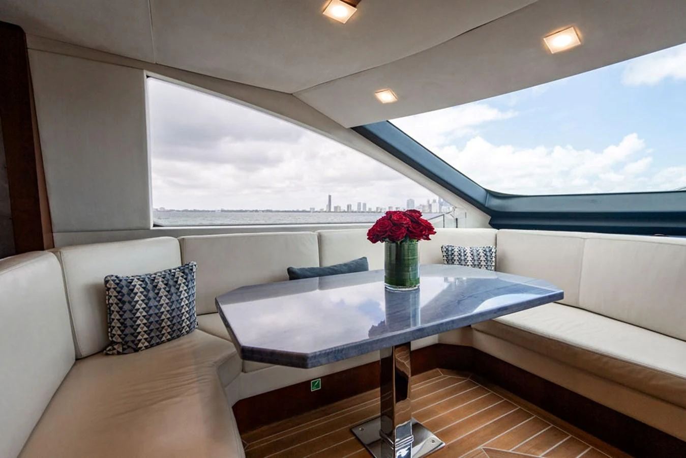 The yacht's dining area features a sleek table with a stunning view through large windows. aboard BEAUTIFUL M Yacht for Sale