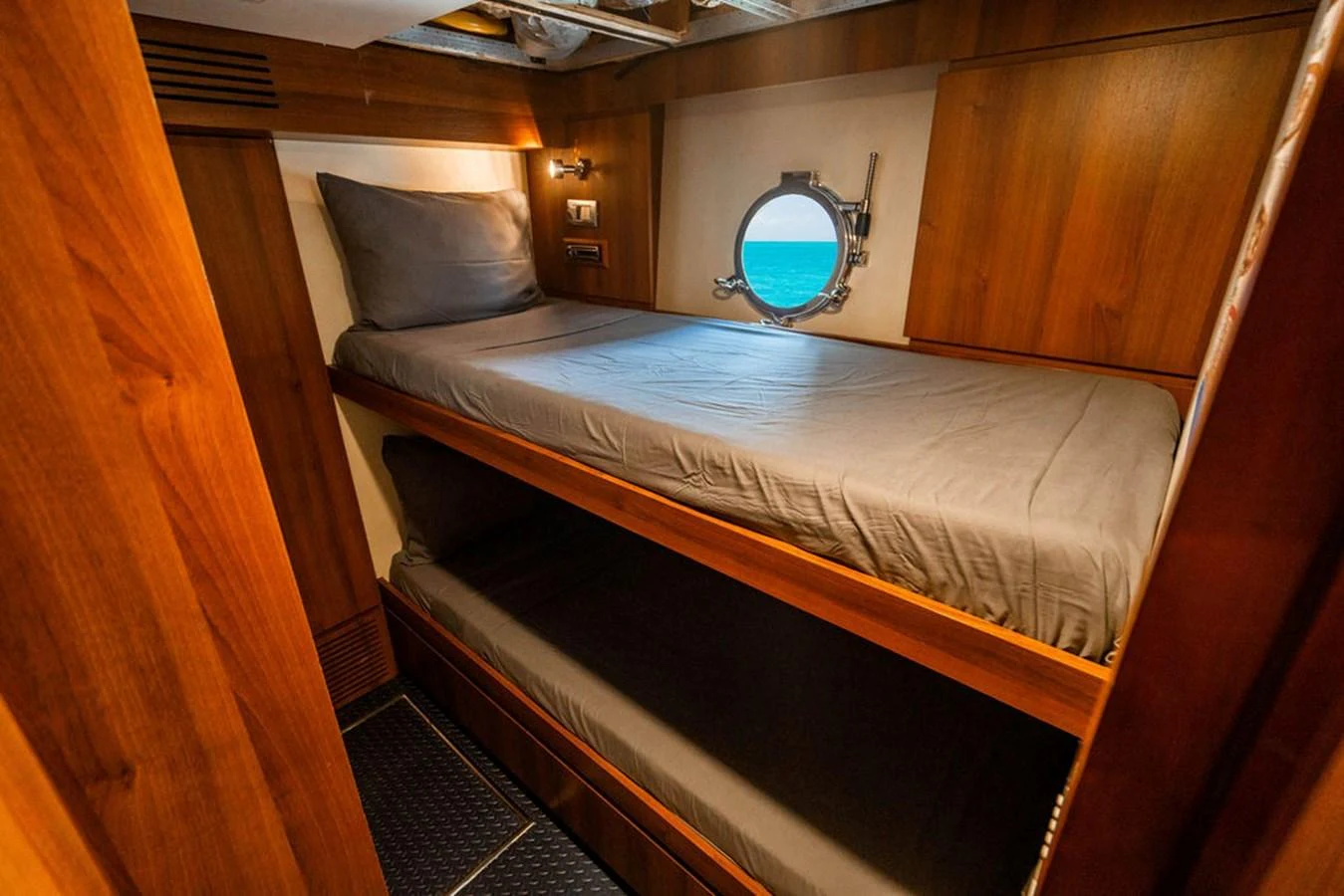 A cozy cabin with wooden finishes and a porthole providing a view of the sea. aboard BEAUTIFUL M Yacht for Sale